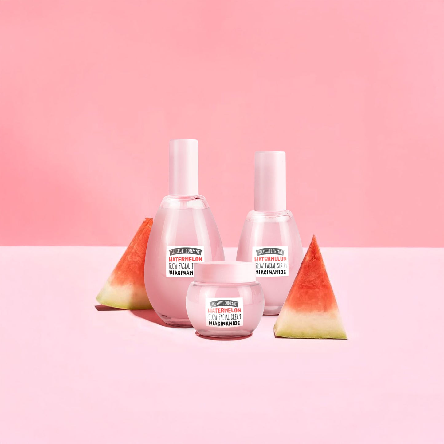Three bottles of skincare cream with watermelon slices on a pink background