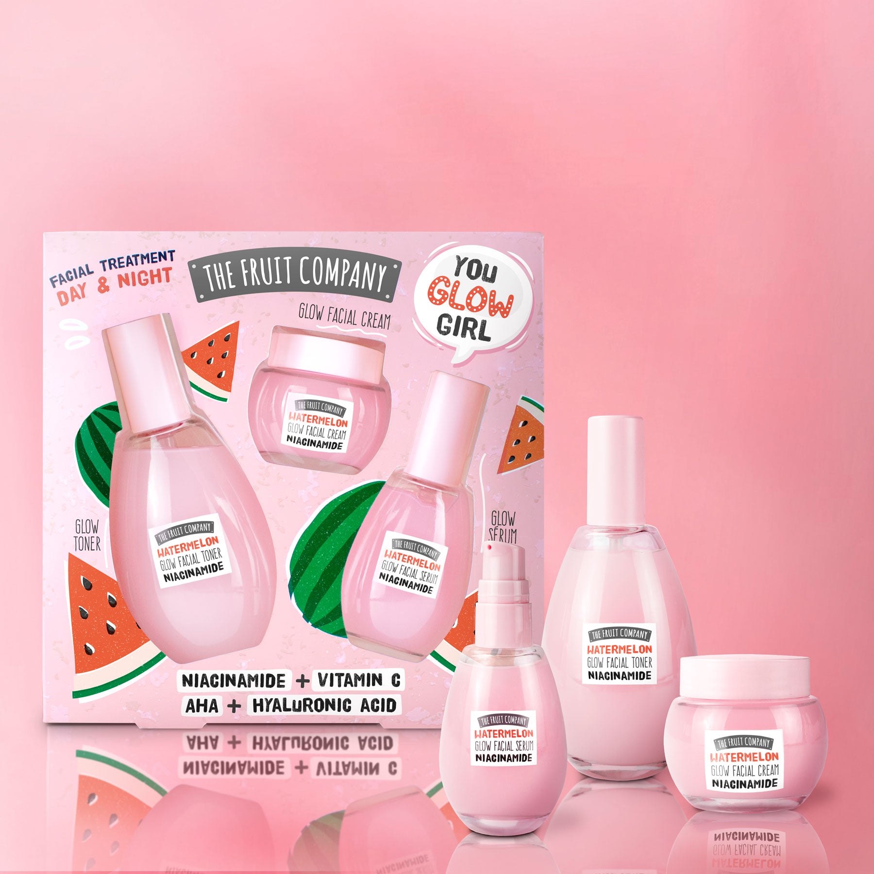 Skincare set with bottles and jars on a pink background, featuring 'The Fruit Company' branding.
