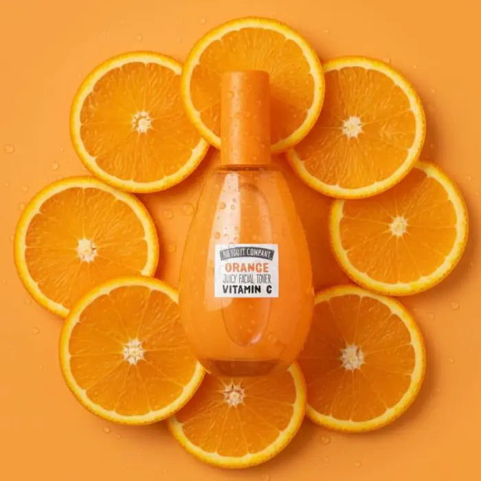 Orange juice bottle surrounded by sliced oranges on an orange background