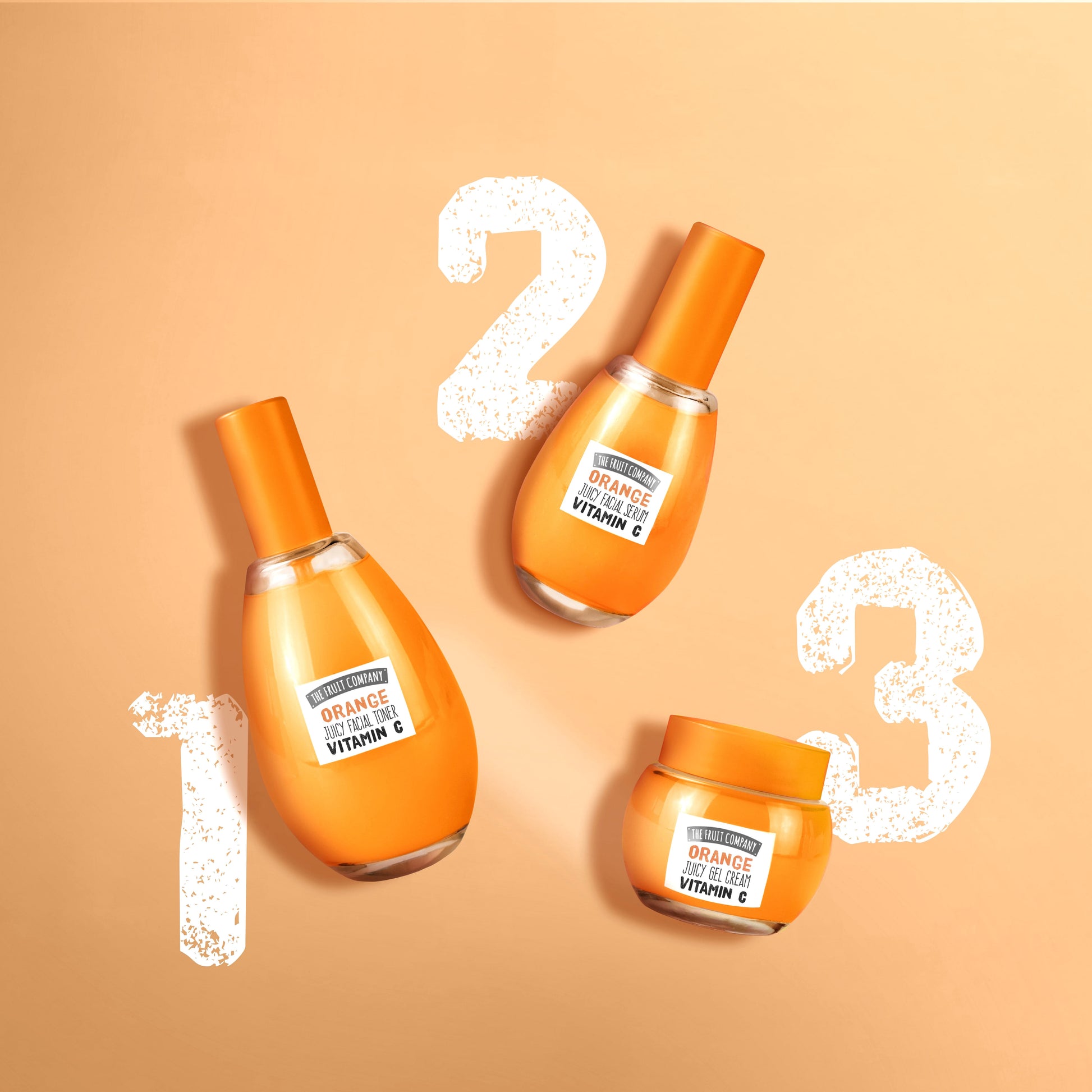 Three orange skincare products with a beige background