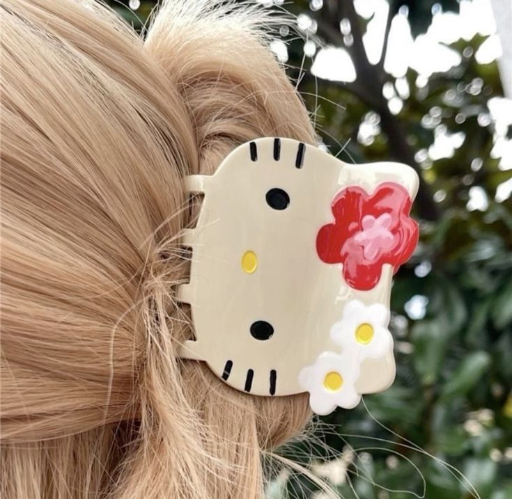Hair clip with a cartoon design featuring flowers in a blurred outdoor setting