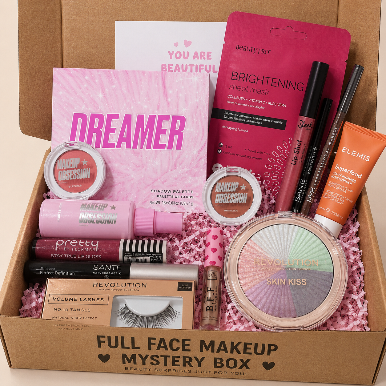 Makeup mystery box with various beauty products including a 'Dreamer' palette and 'Skin Kiss' compact.