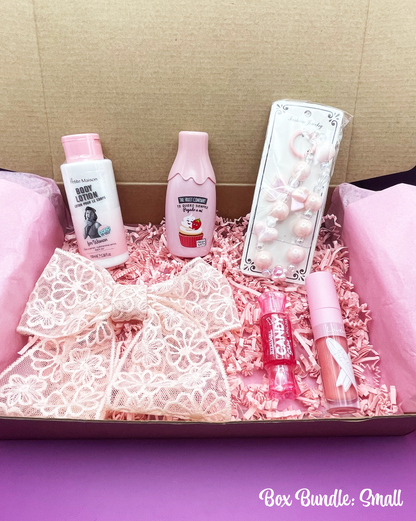 A variety of pink-themed items including makeup, beauty care products, and fashion accessories arranged neatly inside a pink box with a 'Box Bundle: Big' label.