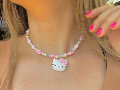 Necklace with a Hello Kitty pendant worn by a person with pink nail polish.