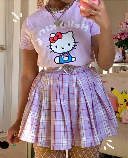 Person wearing a purple t-shirt with a cartoon character and a plaid skirt.