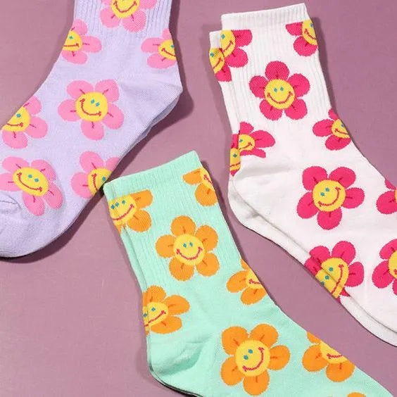 Three pairs of socks with floral designs on a pink background